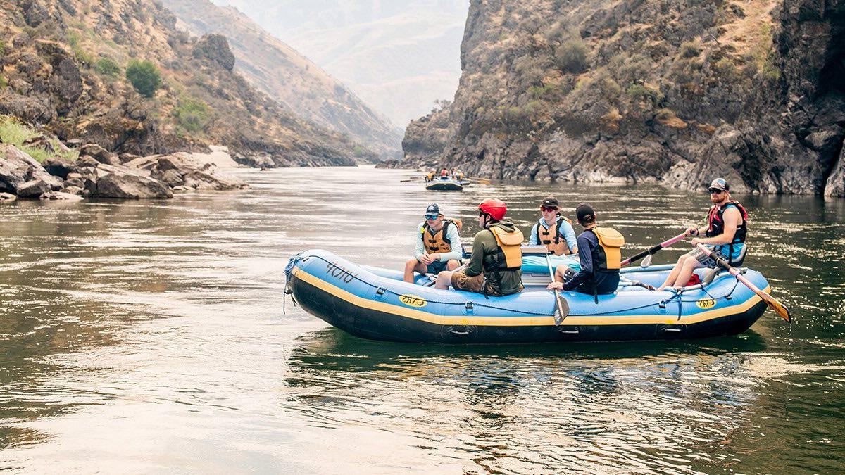 Five guys in a raft in the middle of a river